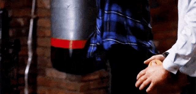 a man is holding a woman 's hand while standing next to a punching bag .