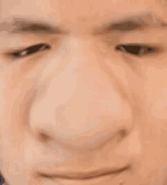 a close up of a man 's face with his eyes closed and a large nose .