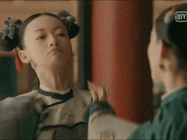 a woman is looking at herself in a mirror and making a face .