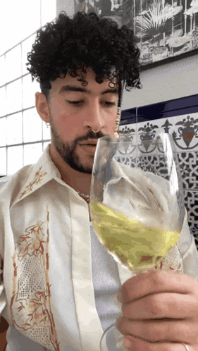 a man with curly hair is drinking from a glass of wine