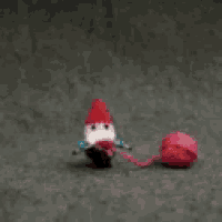 a stuffed gnome is holding a ball of pink yarn .
