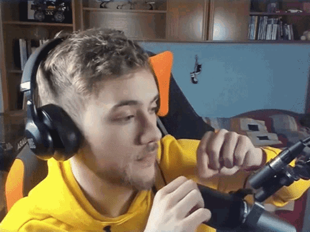 a man wearing headphones and a yellow sweatshirt with the word assault on it