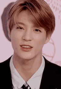 a young man wearing a suit and tie is smiling