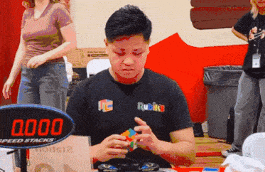 a man wearing a rubik 's t-shirt is playing with a rubik 's cube