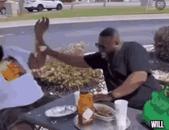 a group of men are sitting at a table with food and drinks .