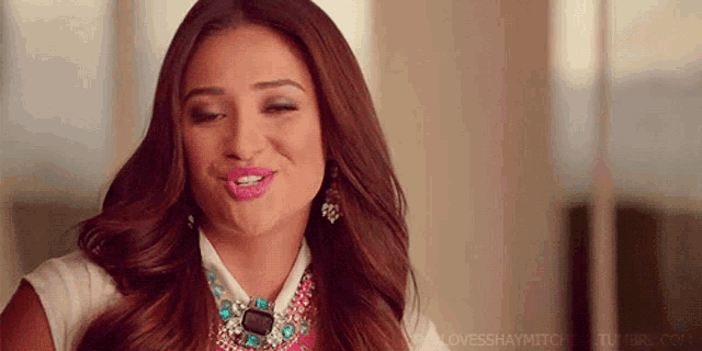 a woman wearing a necklace and earrings is making a face .