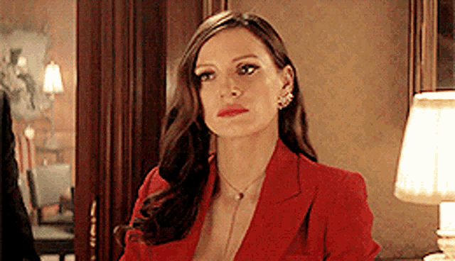a woman in a red jacket is standing next to a lamp .