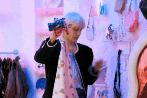 a man in a black jacket is holding a scarf around his neck while standing in front of a mirror in a store .