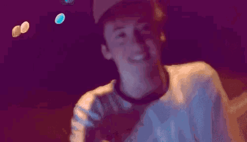 a man wearing a hat and a white shirt is eating a piece of pizza in a blurry photo .