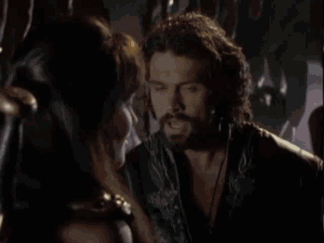 a man with a beard is talking to a woman who says " i do "