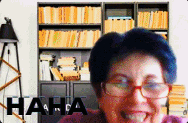 a woman wearing glasses is laughing in front of a bookshelf with the word haha in the corner