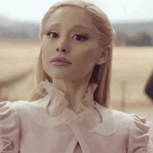 a close up of a woman 's face wearing a pink dress and ruffled collar .