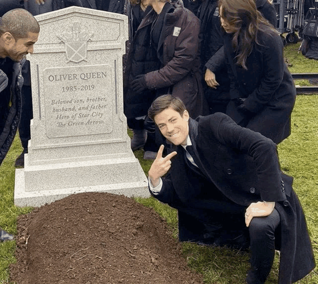 a man kneeling in front of a gravestone that says oliver queen