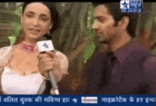 a man is holding a microphone while talking to a woman on a television screen