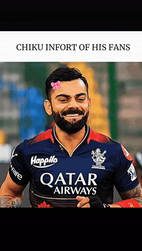 a man with a beard wearing a qatar airways shirt smiles