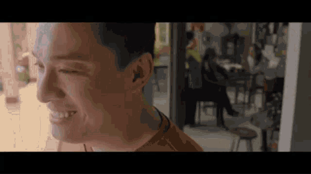 a man is smiling in a room with people sitting at tables .