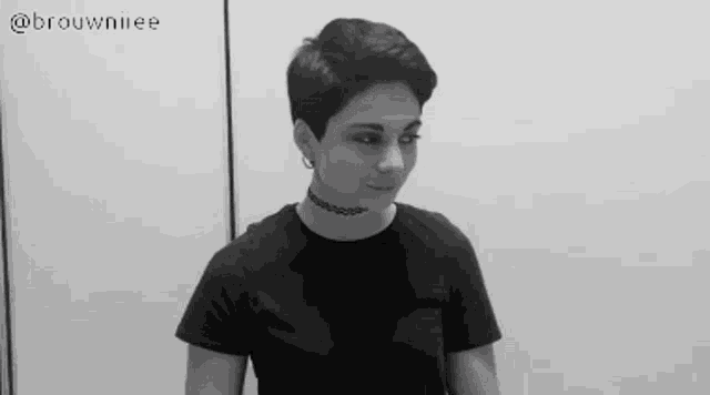 a woman with short hair is wearing a choker and a black shirt .