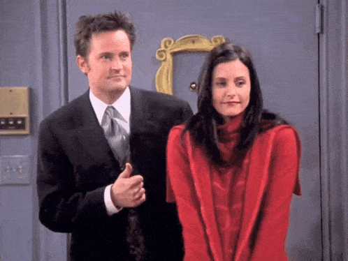 a man in a suit and tie and a woman in a red sweater are standing next to each other