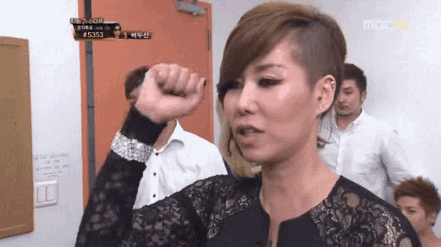 a woman with a shaved head holds her fist up in front of a sign that says mbc