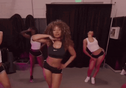 a woman in a nike sports bra is dancing in a gym
