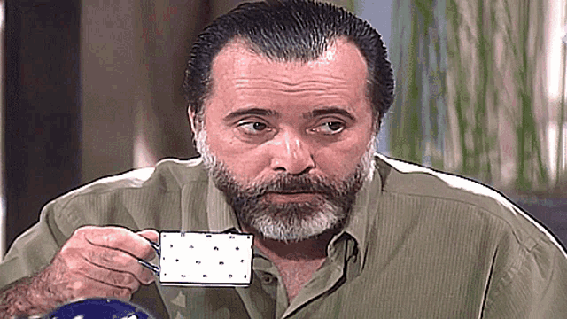 a man with a beard is holding a cup of coffee with the letter m on it