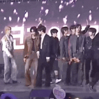 a group of young men are standing on a stage in front of a crowd .