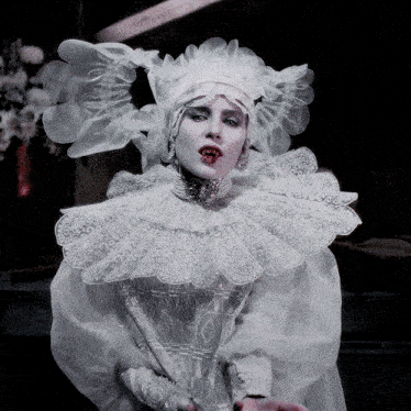 a woman in a white dress with a ruffled collar and hat