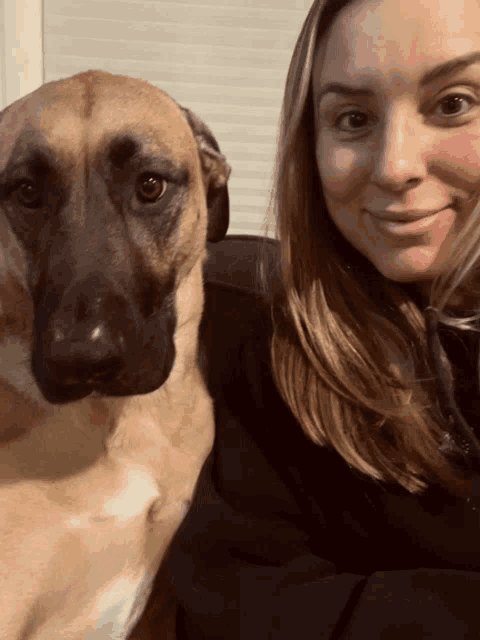 a woman is posing for a picture with a brown dog