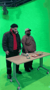 two men are standing at a table with snacks on it