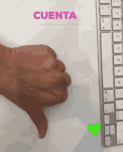 a hand is giving a thumbs down sign in front of a keyboard
