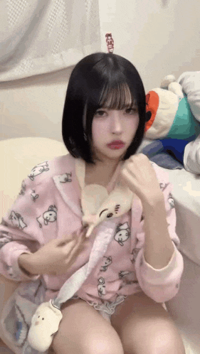 a girl is sitting on a bed holding a stuffed animal
