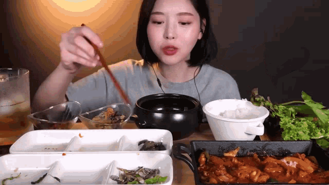 a woman is eating a meal with chopsticks and a bowl of rice