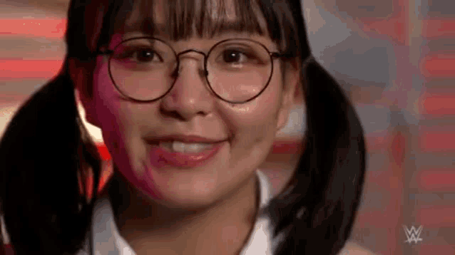 a close up of a young woman wearing glasses and pigtails .