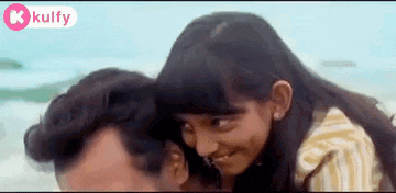 a man and a girl are standing next to each other on the beach .