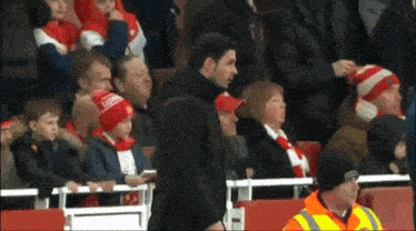 a man wearing a hat that says ' arsenal ' on it stands in front of a crowd