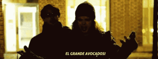 a man and a woman are standing in front of a brick building and the woman says el grande avocados