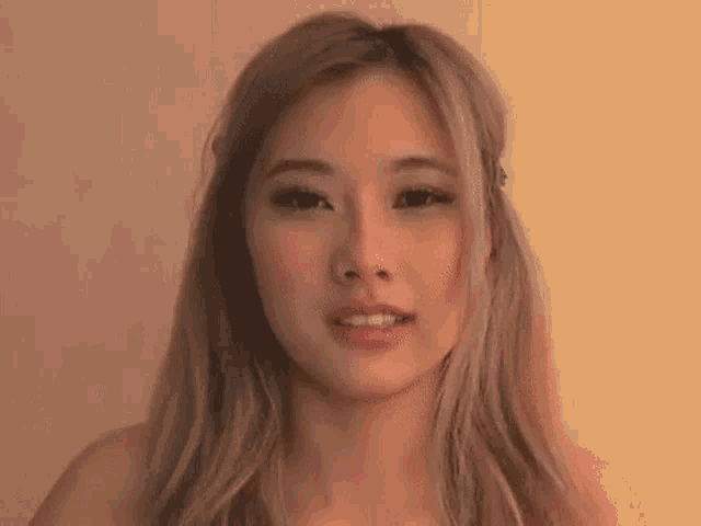 a close up of a woman 's face with blonde hair and a brown background .