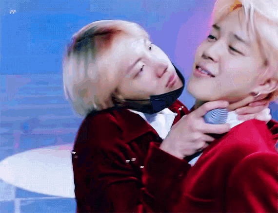 a man in a red jacket is holding another man 's neck while another man looks on