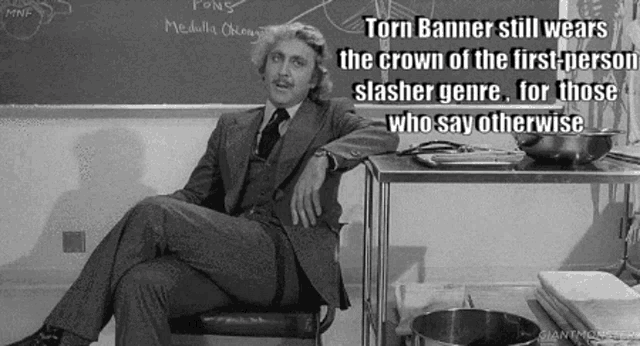 a man in a suit and tie is sitting in front of a blackboard