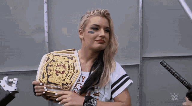 a woman holding a wrestling championship belt that says ' intercontinental ' on it