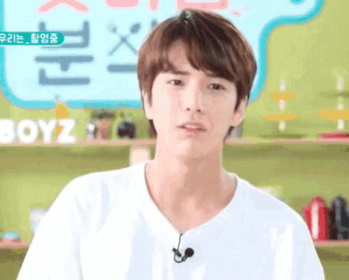 a young man wearing a white shirt with a microphone on his neck