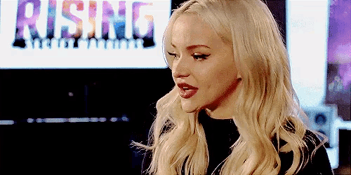a woman with blonde hair stands in front of a sign that says rising