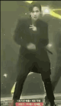 a man in a black suit stands on a stage