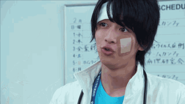 a person with a bandage on their face stands in front of a schedule board