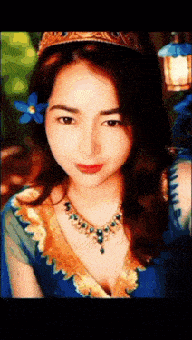 a woman with a blue flower in her hair is wearing a crown