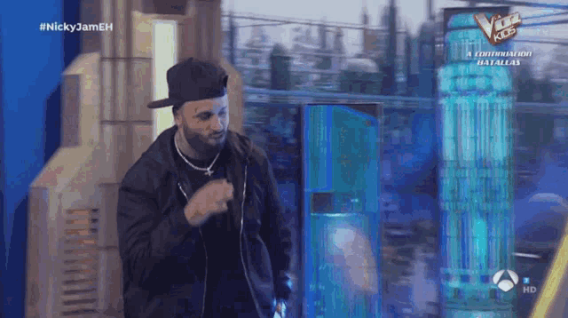 a man in a baseball cap is dancing in front of a sign that says the voice