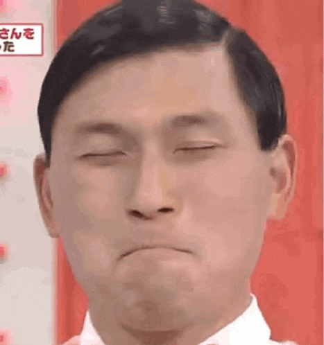 a man with his eyes closed is making a funny face .