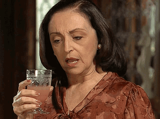 a woman is holding a glass of pink liquid