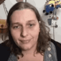 a woman with long hair is smiling in front of a wall with stuffed minions on it .