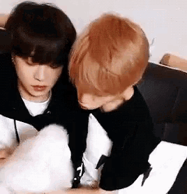 two young men are sitting next to each other on a couch and hugging .